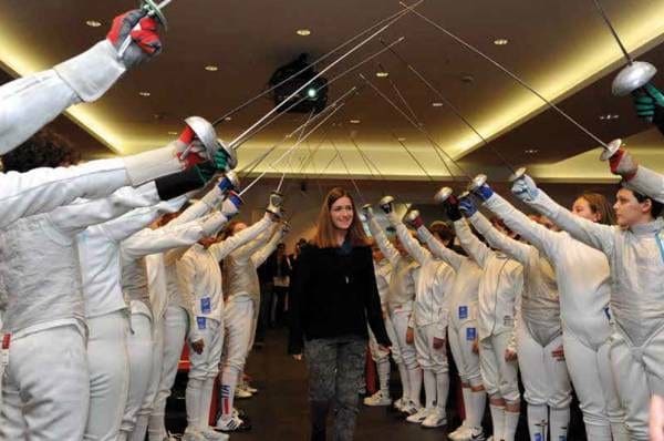Martina Caironi walks under an arch of raised swords held by young fencers at the 2013 Edoardo Mangiarotti Award